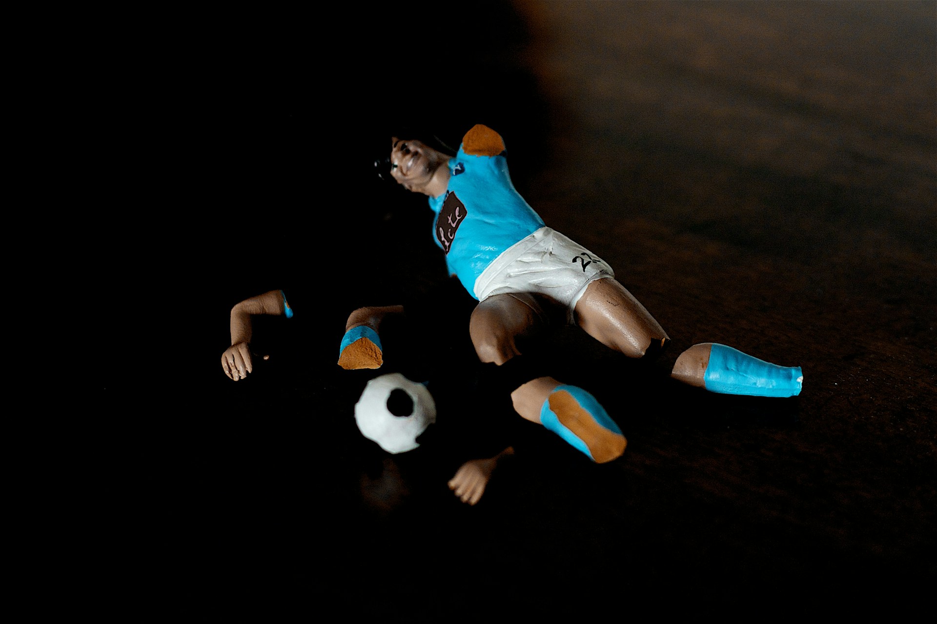 Photo of a toy footbal player broken into pieces.